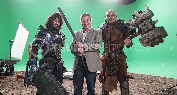 Behind the scenes of 'From the Veil', Rodric David poses in front of green screen with a knight and an orc